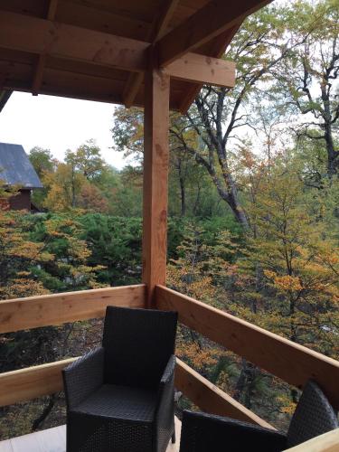 a porch with chairs and a view of the woods at Complejo Turistico Los Hualles in Las Trancas