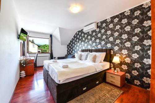 a bedroom with a large bed with a floral wallpaper at Pansion Villa Cancar in Grabovac