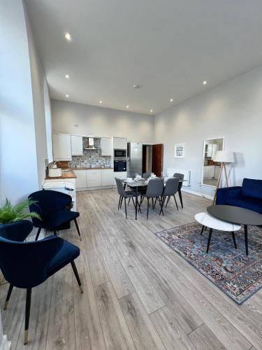 a living room with tables and chairs and a kitchen at Welsh Getaway Apartment - Town Centre in Merthyr Tydfil