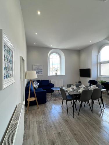 a living room with a table and a blue couch at Welsh Getaway Apartment - Town Centre in Merthyr Tydfil
