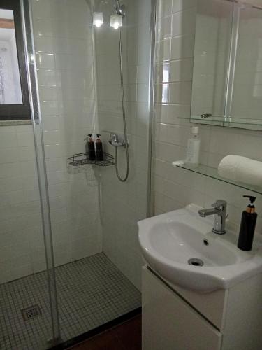 a white bathroom with a shower and a sink at Quinta Pedreira dos Anjos in Provesende