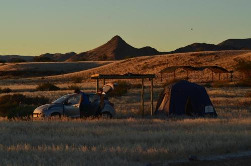 a tent and a car in the middle of a field at Neuhof Portion 2 Campsite in Sesriem