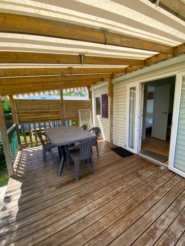 un patio avec une table et des chaises sur une terrasse dans l'établissement Camping Le Bois D'Amour, à l'Île-Tudy