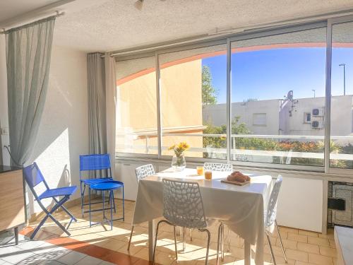 une salle à manger avec une table et des chaises et une grande fenêtre dans l'établissement Rosae by POM, piscine, pkg, au Cap d'Agde