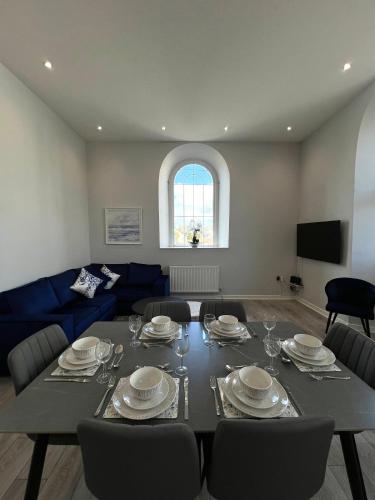 a living room with a table and a blue couch at Welsh Getaway Apartment - Town Centre in Merthyr Tydfil