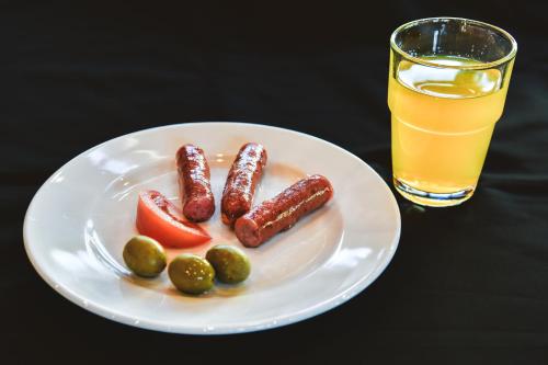 trois saucisses et des tomates dans une assiette avec un verre de jus dans l'établissement Villa Čančar, à Grabovac