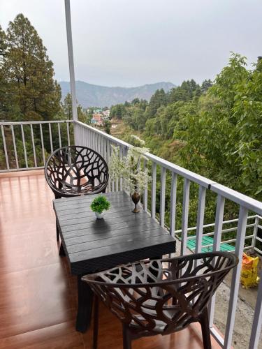 a table and chairs on a balcony with a view at The Nest Homestay in Rāmgarh