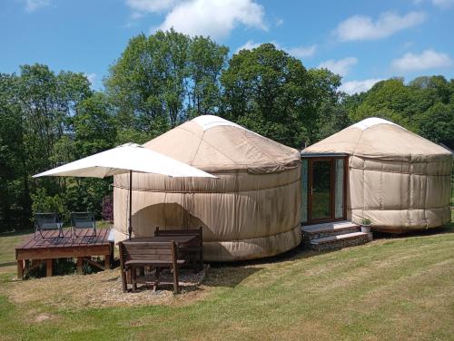 deux tentes yourtes avec un banc et une table dans l'établissement La yourte au pré du réu, à Planchez