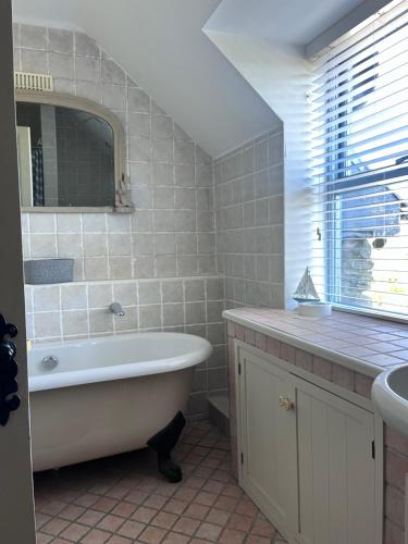 a bathroom with a tub and a sink and a mirror at Schull Coastal rural hideaway 5 night min in Derreennatra