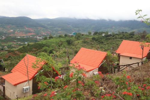 three houses with orange roofs on a hill at Dreamers Garden Farmstay in Hoat