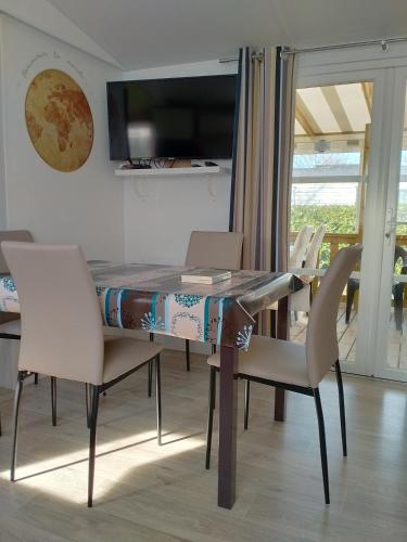 - une table à manger avec des chaises et un ordinateur portable dans l'établissement Mobil home 3 chambres, à Gastes