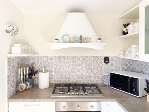 a kitchen with a stove and a microwave at Rainbow Maison in SantʼAgata sui Due Golfi