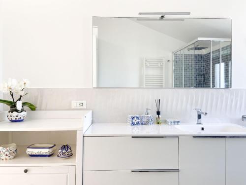 a white kitchen with a sink and a mirror at Rainbow Maison in SantʼAgata sui Due Golfi
