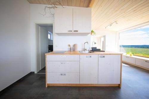 a kitchen with white cabinets and a large window at Ferienhaus am Flugplatz, umgeben von Natur in Kühndorf