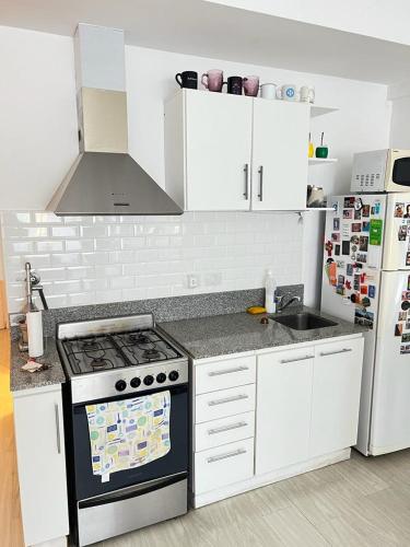 a white kitchen with a stove and a refrigerator at Delta House in Tigre