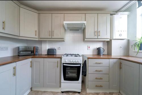 a kitchen with white cabinets and a stove top oven at Sleek 2 Bedroom Apartment in Belfast