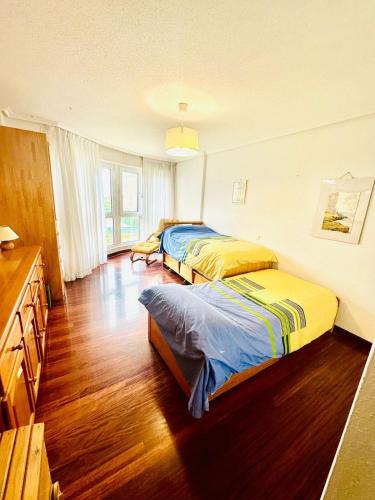 two beds in a room with wooden floors at Berria Beach and Pool in Santoña