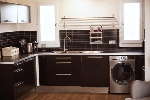 une cuisine avec un évier et une machine à laver dans l'établissement Appt 80 M2 VUE PORT - BAIGNOIRE BALNEO, à Gruissan
