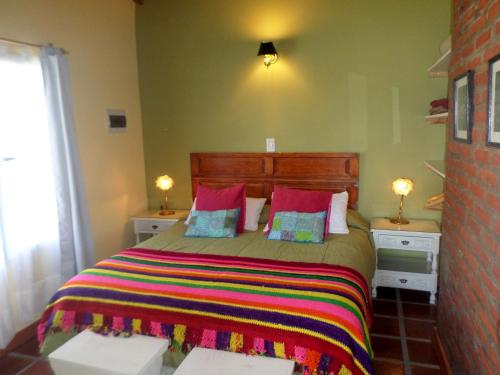 a bedroom with a large bed with a colorful blanket at Complejo Dulcería El Cazador y cabañas in Tandil