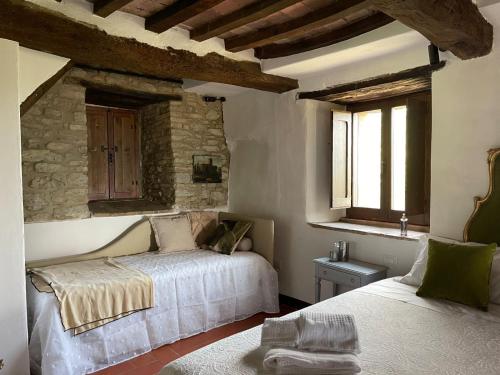 a bedroom with two beds and a stone wall at Ca' di Nieri The Saints' Lodge in Monte Santa Maria Tiberina
