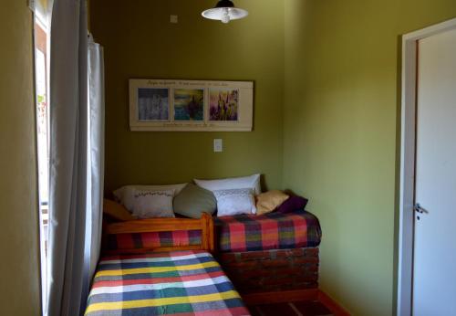 two beds in a room with green walls at Complejo Dulcería El Cazador y cabañas in Tandil