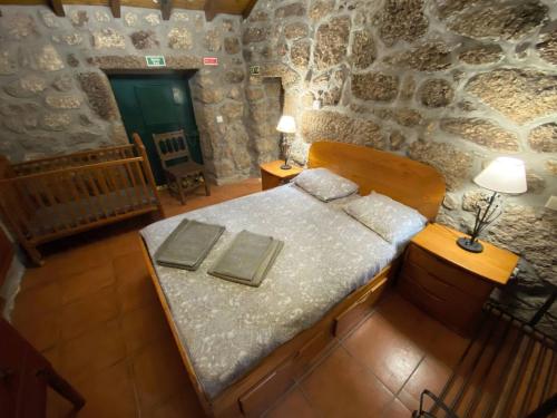 a bedroom with a bed in a stone wall at Refúgio Rural no Gerês - Casa Araujo de Sousa in Terras de Bouro