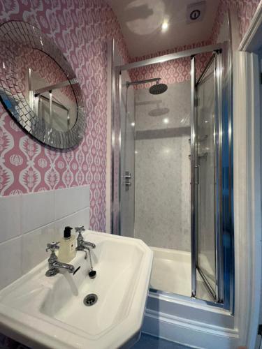 a bathroom with a sink and a shower and a mirror at The Old Post Office B&B in Longwitton