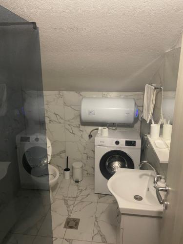a bathroom with a washing machine and a sink at Bayview Apartments in Drobnići