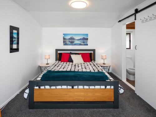 a bedroom with a large bed with green sheets and red pillows at Beach House with Spacious Backyard in Papamoa in Papamoa
