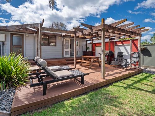 a wooden deck with a pergola and a patio at Beach House with Spacious Backyard in Papamoa in Papamoa