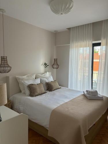 een slaapkamer met een groot wit bed met een raam bij RookieC Two Bedroom peaceful location old town AC in Cascais