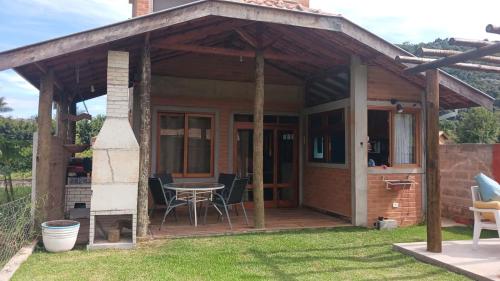 ein Haus mit einer Terrasse mit Tisch und Stühlen in der Unterkunft Casa Quinta do Paiol in São Bento do Sapucaí