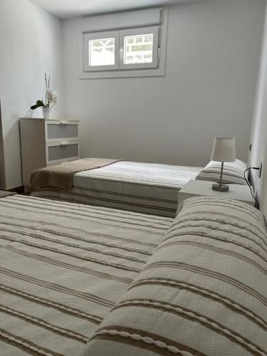 a white bedroom with two beds and a window at Casa Kiros in Cangas de Morrazo
