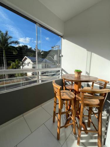 a balcony with a wooden table and chairs and a window at Apê Conforto in Brusque
