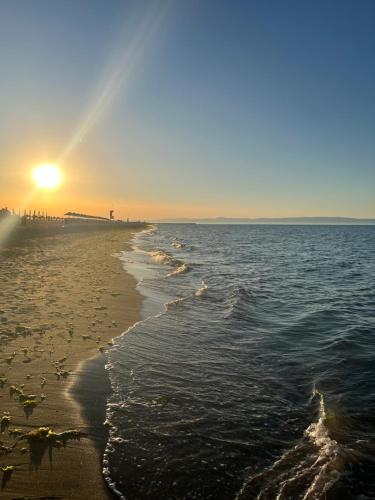 a beach with the sun rising over the ocean at Vista Mare Luxury Rooms & Apartments in Margherita di Savoia