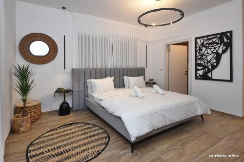 a bedroom with a bed with white sheets and a mirror at סוויטות בל - סוויטות יוקרה עם בריכה פרטית in Safed