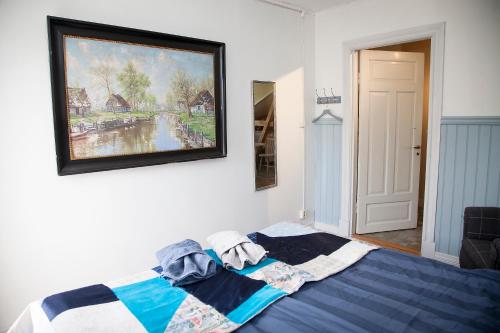 a bedroom with a blue bed with a painting on the wall at Boråkra Bed & Breakfast in Karlskrona