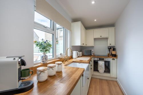 a kitchen with white cabinets and a wooden counter top at Keel Cottage & Dog Friendly in Nairn