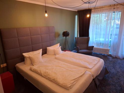 a bedroom with a large bed and a chair at Gästezimmer im Parkhotel Wehrle in Triberg