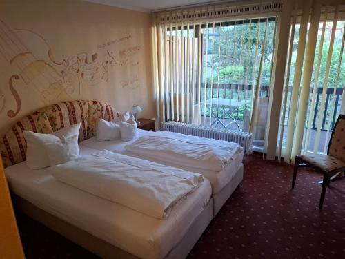 a bedroom with two beds and a chair and windows at Gästezimmer im Parkhotel Wehrle in Triberg