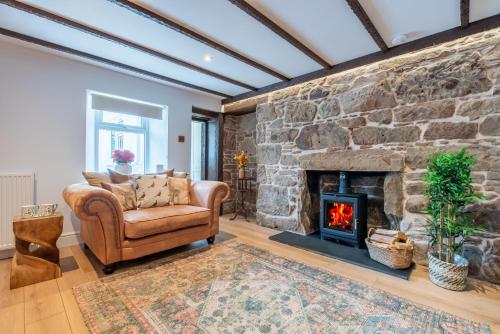 a living room with a stone wall with a chair and a fireplace at Keel Cottage & Dog Friendly in Nairn