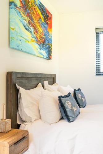 a bed with white pillows and a painting on the wall at Waterfield House B&B in Dorchester