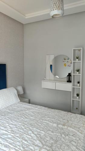 a white bedroom with a bed and a mirror at Appartement costamar à 200m de la plage in Martil