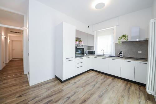 a white kitchen with white cabinets and a wooden floor at Domus Garda Relax in Garda