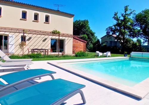 a swimming pool with two chairs and a house at La petite maison de Valérie proche château de la Rode, du Domaine de Flore et du Lac Saint Ferréol in Lempaut