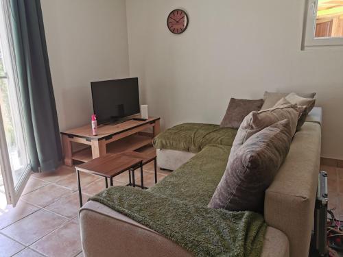 a living room with a couch and a tv at Hébergement avec jardin in Le Garn