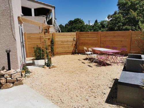 a backyard with a table and a fence at Hébergement avec jardin in Le Garn