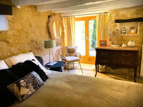 a bedroom with a bed and a chair and a window at Gîte Les Pierres Blondes in Groléjac