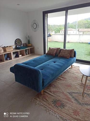 - un canapé bleu dans une chambre avec une grande fenêtre dans l'établissement Agréable villa familiale avec piscine, à Prades-le-Lez