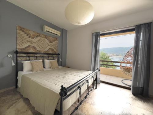 a bedroom with a large bed and a large window at Villa Irene in Poros
